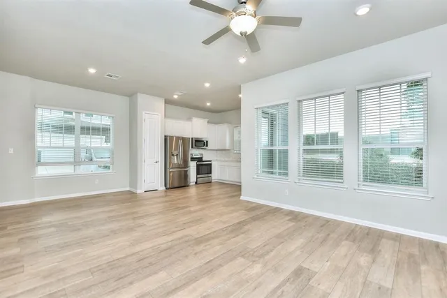 a view of an empty room with a window and wooden floor