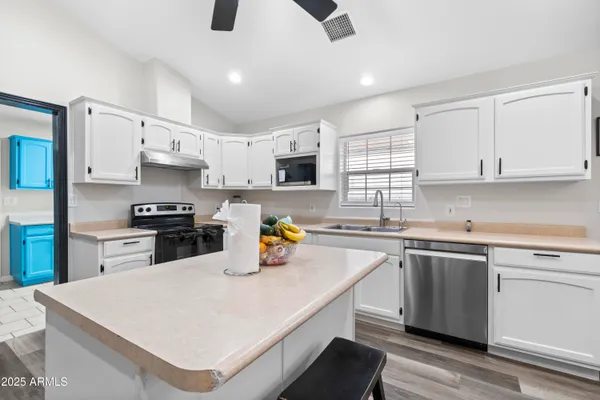 a kitchen with a refrigerator a sink dishwasher a stove and white cabinets with wooden floor