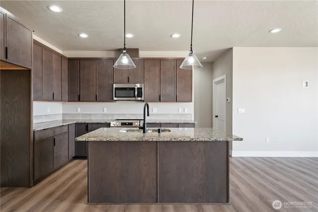 a kitchen with kitchen island granite countertop a sink a counter top space stainless steel appliances and cabinets