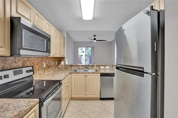 a kitchen with granite countertop a refrigerator stove and sink