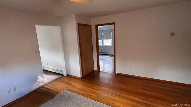 a view of an empty room with wooden floor and closet