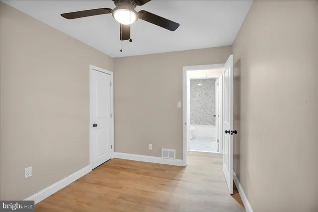 an empty room with closet and a chandelier fan