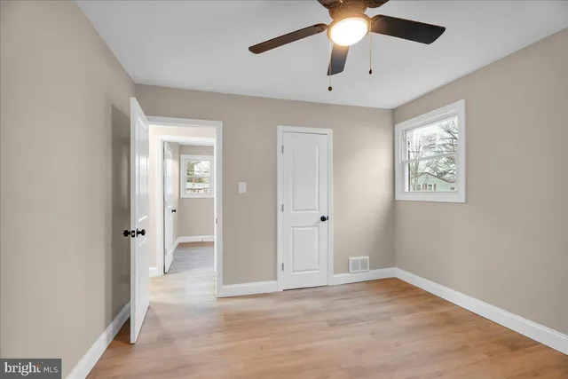 wooden floor in an empty room with a chandelier fan