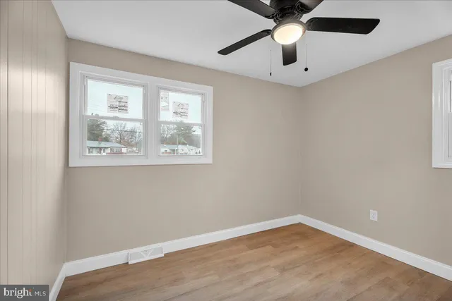 a view of an empty room with window and a chandelier fan
