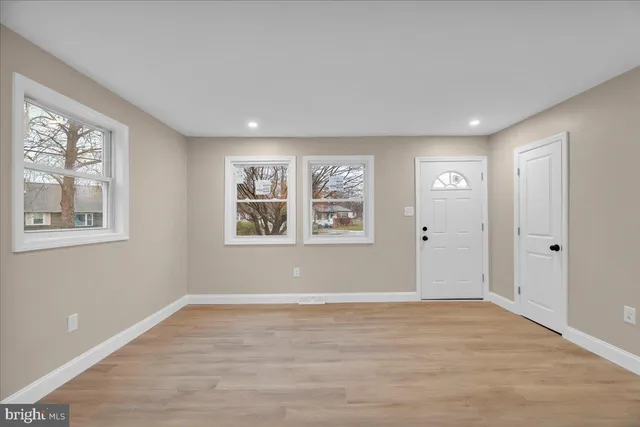 a view of an empty room with window and wooden floor