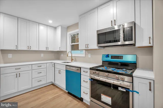 a kitchen with cabinets stainless steel appliances and wooden floor