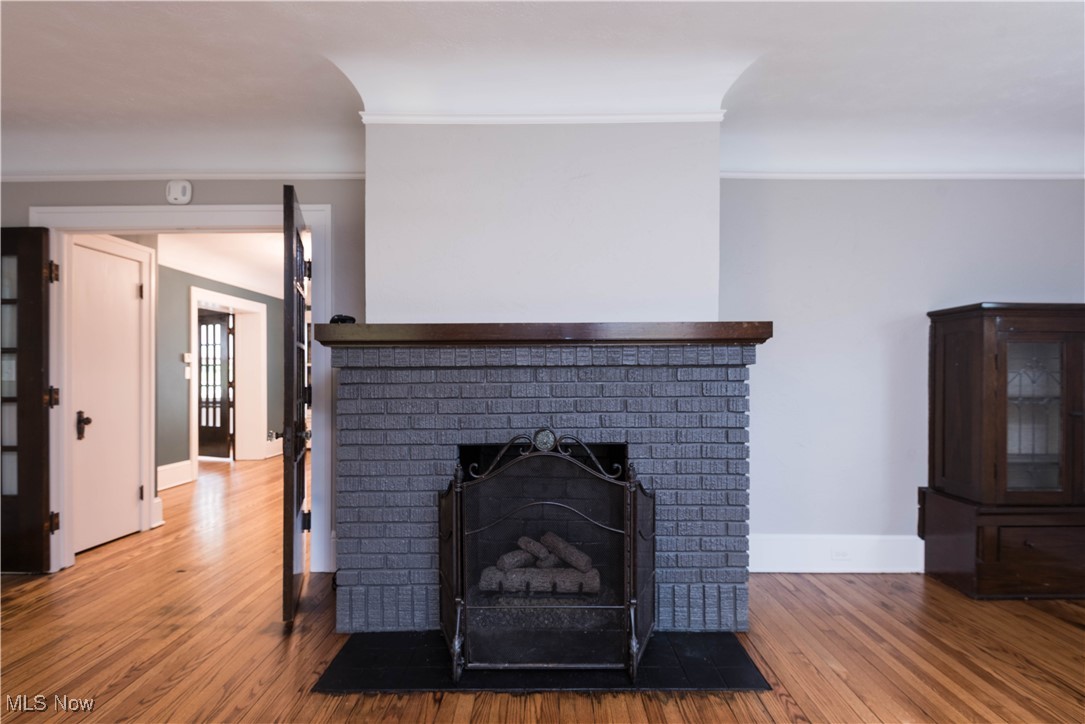 7003 Brecksville Road Independence, OH 44131 - Photo 6 of 35 Detailed view of wood finished floors, a brick fireplace, and ornamental molding
