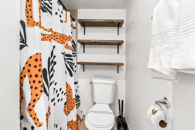 a white toilet sitting next to a white curtain