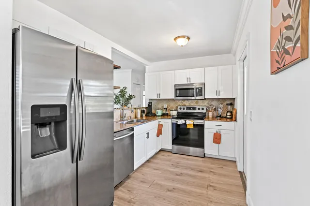a kitchen with stainless steel appliances granite countertop a refrigerator a stove and a sink with wooden floor
