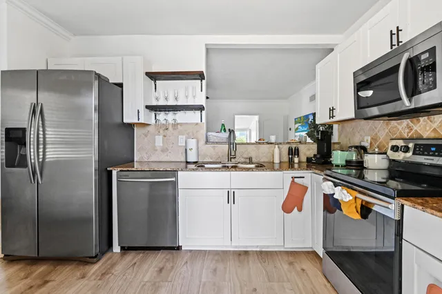 a kitchen with stainless steel appliances granite countertop a refrigerator a stove top oven a sink and dishwasher