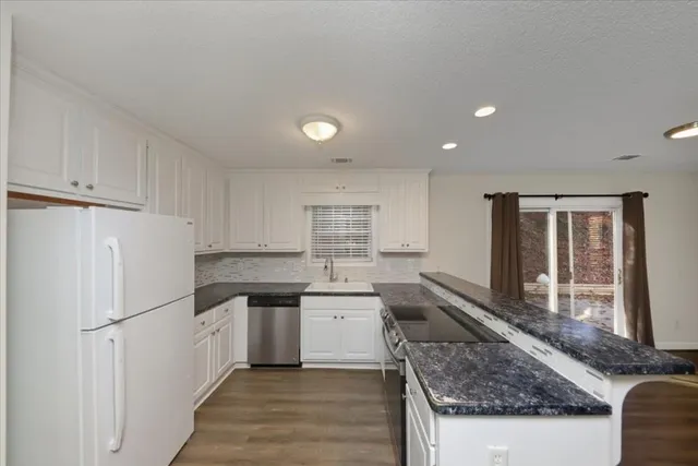 a kitchen with granite countertop cabinets stainless steel appliances and a window