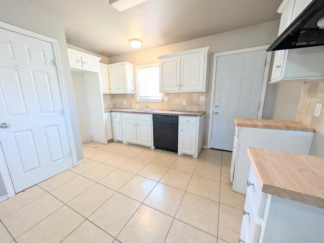 a kitchen with a sink a stove top oven and white cabinets