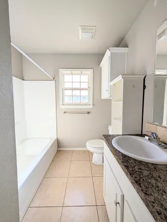 a bathroom with a granite countertop sink a toilet and bathtub