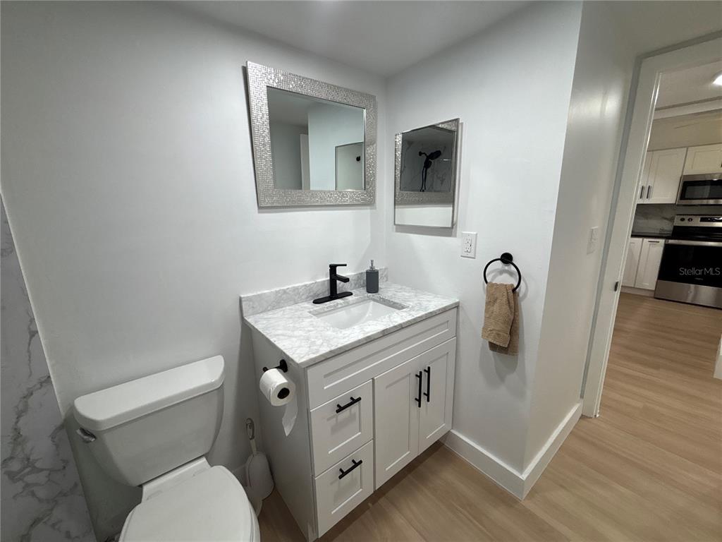 4725 Cove Circle, Unit 405 St. Petersburg, FL 33708 - Photo 14 of 23 a bathroom with a granite countertop toilet sink and mirror