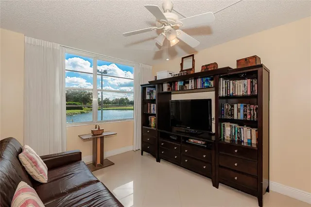 a living room with furniture a flat screen tv and a floor to ceiling window