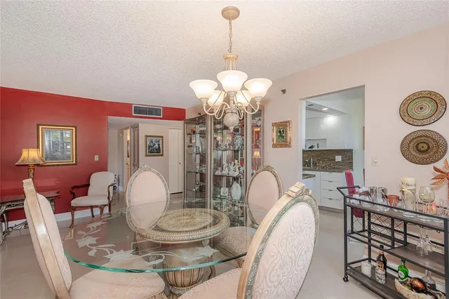 a dining room with wooden floor a chandelier a wooden table and chairs