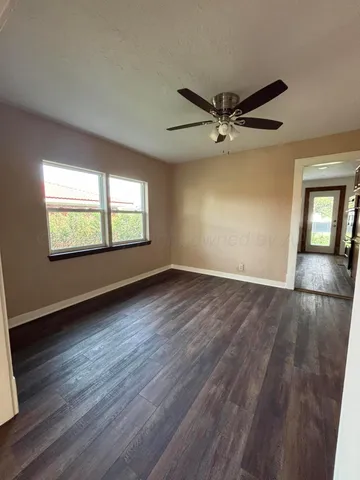 an empty room with wooden floor chandelier and windows