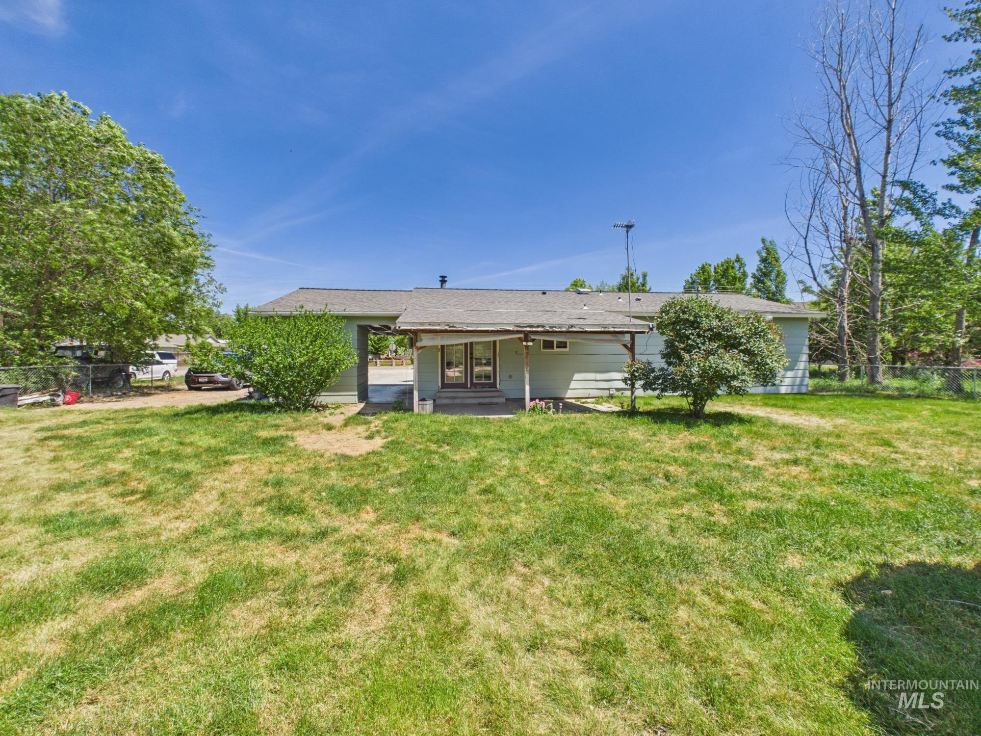 1527 North Plaza Road Emmett, ID 83617 - Photo 2 of 33 Spacious backyard featuring a covered patio, mature perimeter trees, and a light-colored siding exterior