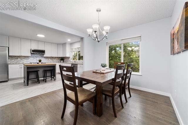 7730 Julynn Road Colorado Springs, CO 80919 - Photo 5 of 48 Dining room with light hardwood / wood-style flooring, sink, a chandelier, and a textured ceiling