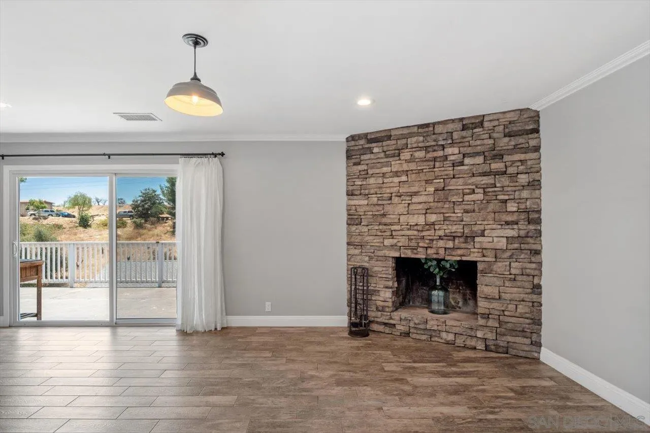 32251 Cole Grade Road Valley Center, CA 92082 - Photo 13 of 54 an empty room with fireplace and wooden floor