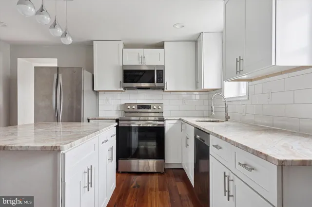 a kitchen with stainless steel appliances granite countertop a sink stove microwave and refrigerator