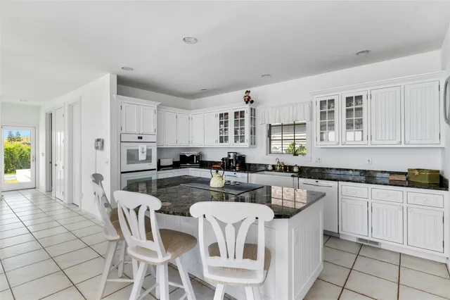 a kitchen with stainless steel appliances granite countertop a stove a sink a dining table and chairs