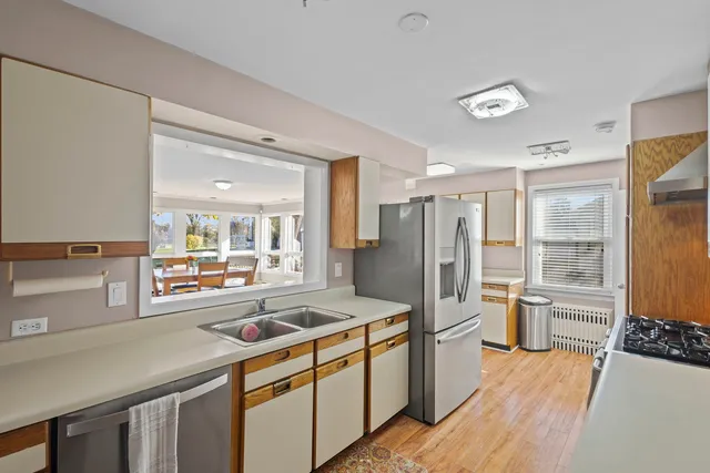 a kitchen with stainless steel appliances a refrigerator a sink a stove and white cabinets with wooden floor