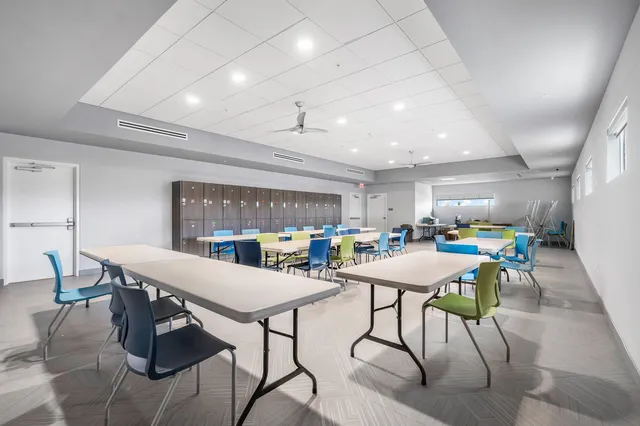 a view of a sign in a yard with potted plants and tree