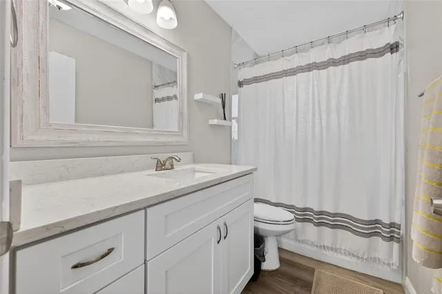 a bathroom with a granite countertop sink a toilet and a shower curtain