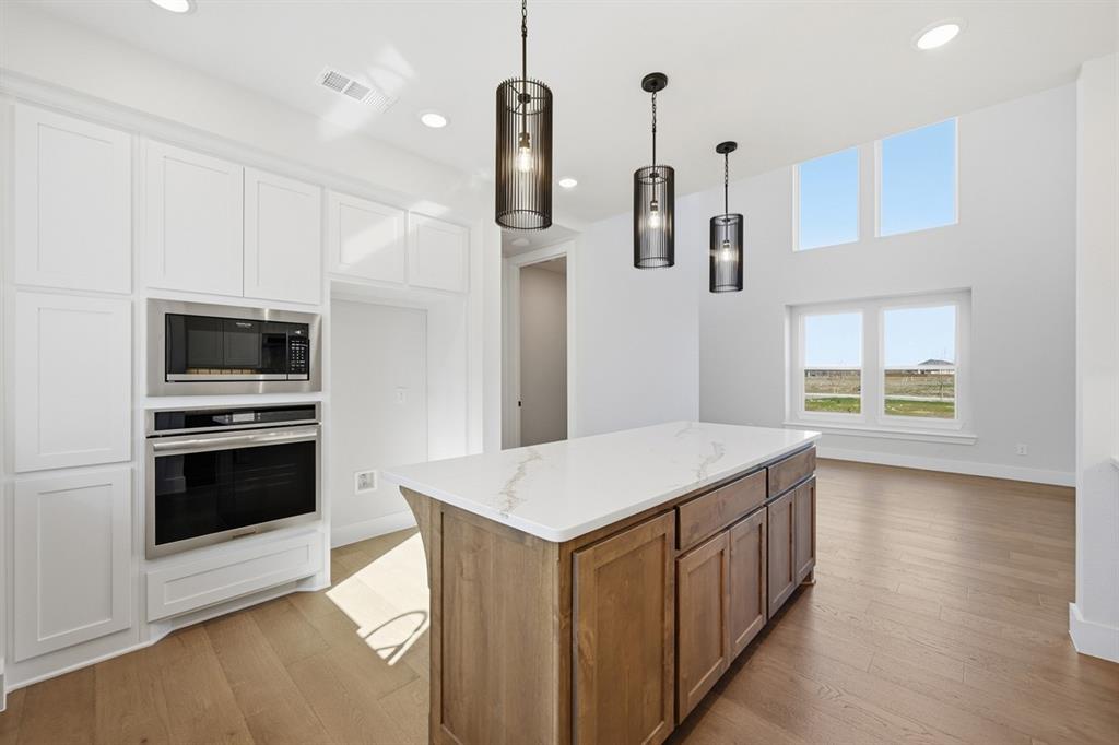 4408 Daisy Lane Prosper, TX 75078 - Photo 5 of 25 a kitchen that has a kitchen island wooden floor and stainless steel appliances