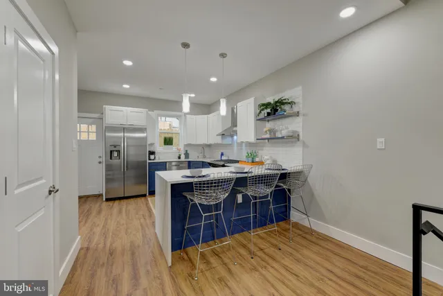 a kitchen with stainless steel appliances granite countertop a refrigerator a sink dishwasher and a stove with wooden floor