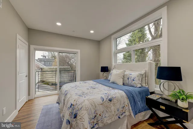 a bedroom with a bed a large window and wooden floor