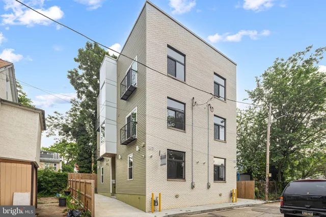 a view of a white apartments with large tree
