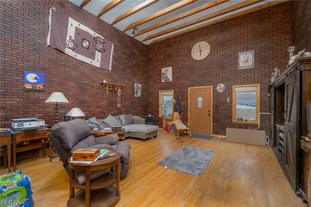 6132 North Canterbury Road Parma, OH 44129 - Photo 21 of 34 Living room with a towering ceiling, brick wall, light hardwood floors, and beam ceiling