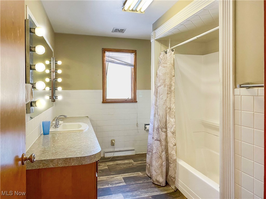 1034 Straub Road West Mansfield, OH 44904 - Photo 11 of 27 Bathroom featuring tile walls, vanity, hardwood / wood-style floors, and shower / bath combination with curtain