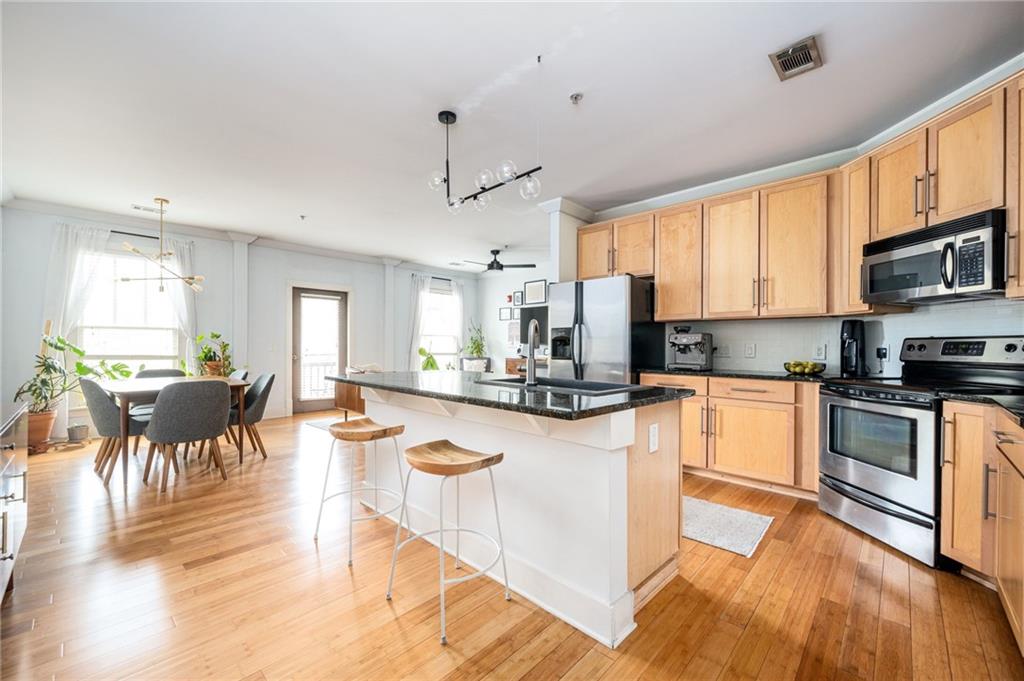 1628 Briarcliff Road Northeast, Unit 9 Atlanta, GA 30306 - Photo 4 of 25 a kitchen with stainless steel appliances granite countertop a stove top oven a sink a dining table and chairs with wooden floor