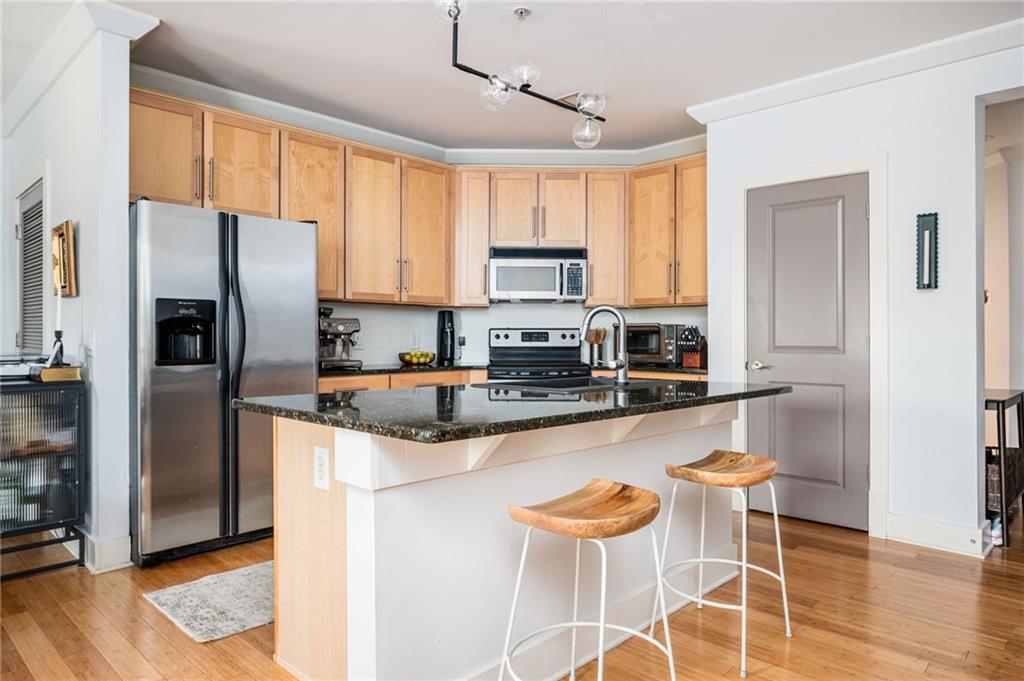 1628 Briarcliff Road Northeast, Unit 9 Atlanta, GA 30306 - Photo 6 of 25 a kitchen with stainless steel appliances granite countertop a stove a refrigerator a sink a dining table and chairs with wooden floor
