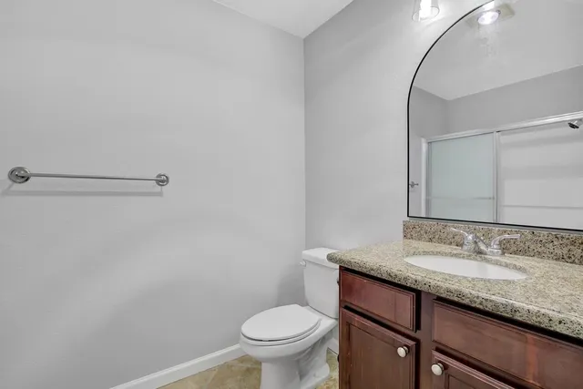 a bathroom with a granite countertop sink toilet and a mirror