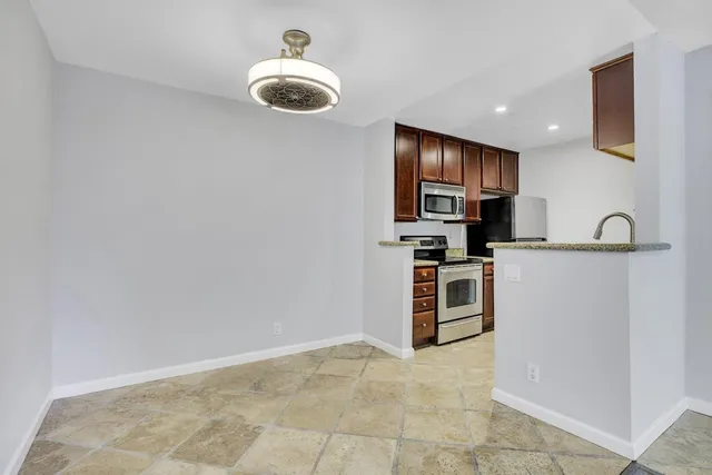 a kitchen with kitchen island stainless steel appliances a stove refrigerator sink and microwave