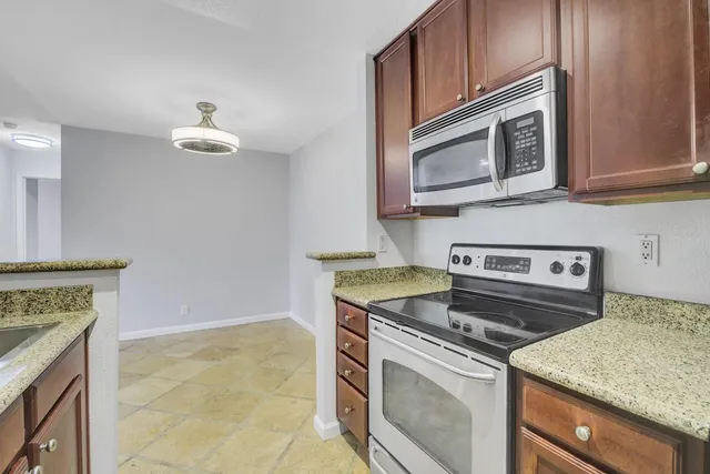 a kitchen with granite countertop a stove top oven microwave and cabinets