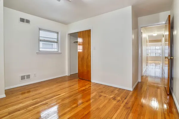 a view of an empty room with wooden floor and a bathroom