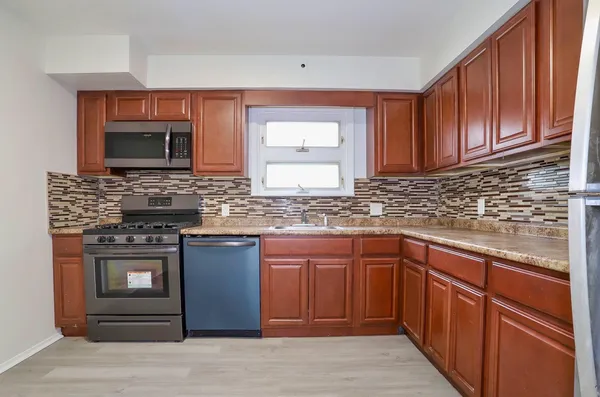 a kitchen with stainless steel appliances granite countertop wooden cabinets stove top oven and sink