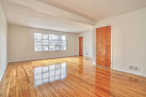 an empty room with wooden floor and windows