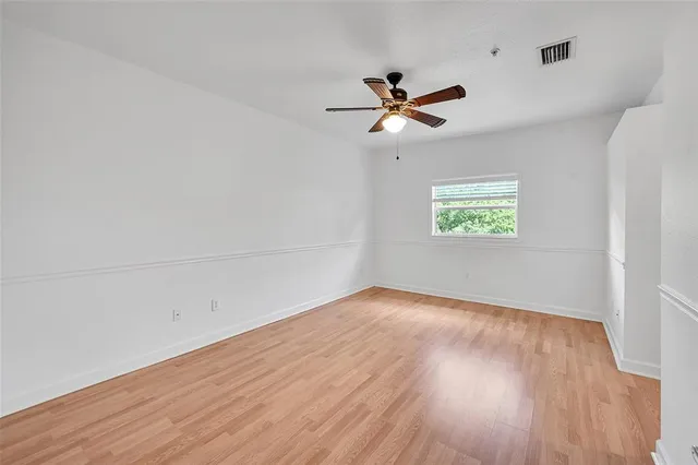 an empty room with wooden floor fan and windows