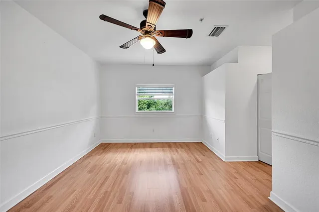 a view of a room with wooden floor and a ceiling fan