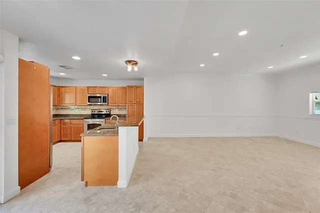 a kitchen with granite countertop a stove a sink and a refrigerator
