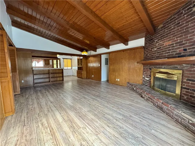 a view of an empty room with wooden floor fireplace and a window