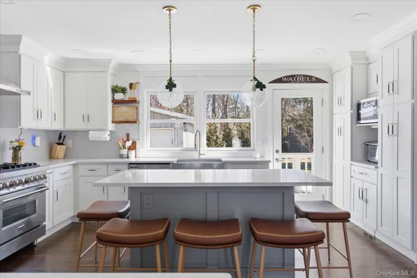 a kitchen with stainless steel appliances a dining table chairs and white cabinets