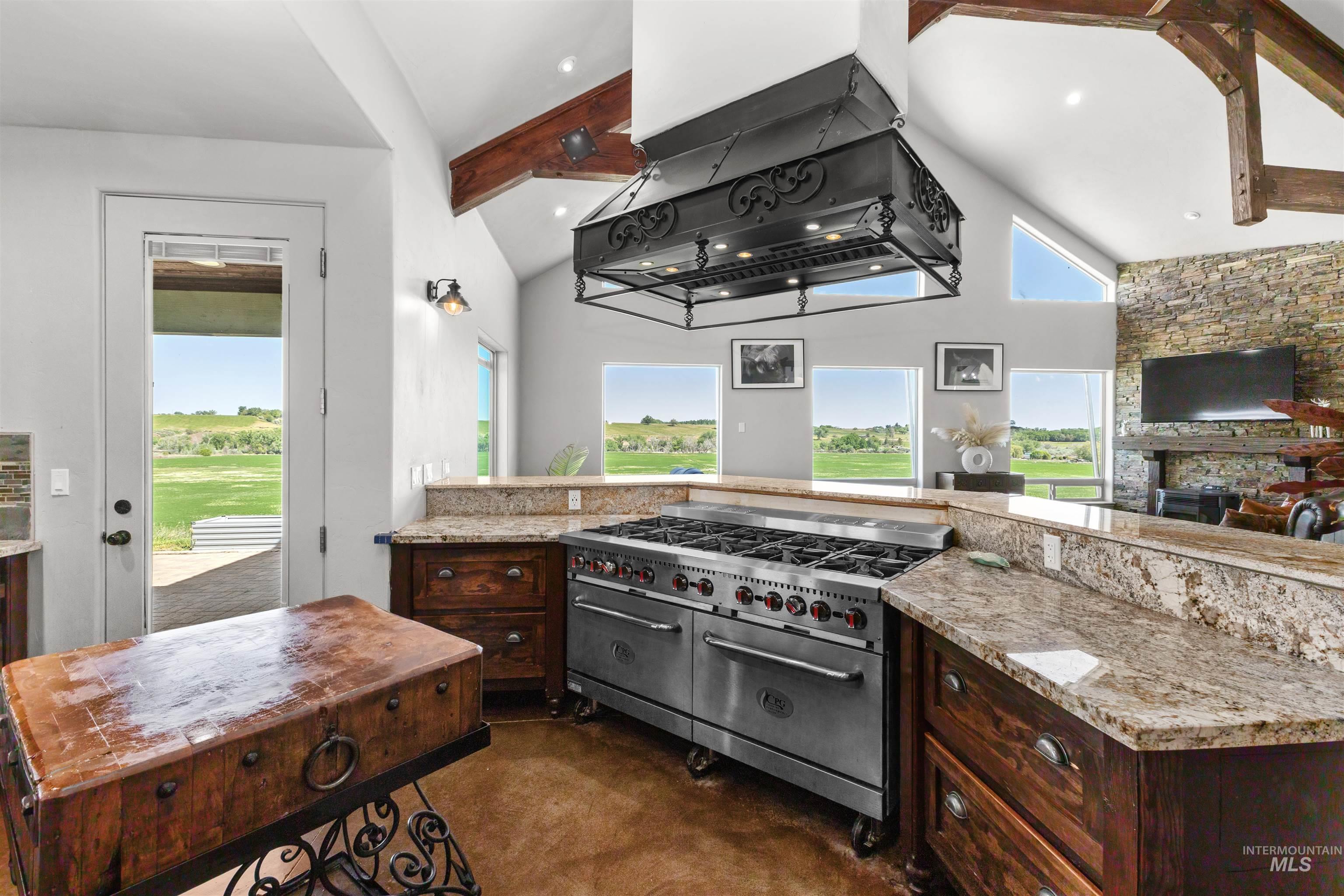 1030 Desert Glen Road Adrian, OR 97901 - Photo 27 of 47 Spacious kitchen featuring an oversized stainless steel range, custom range hood, granite countertops, and rich wood cabinetry