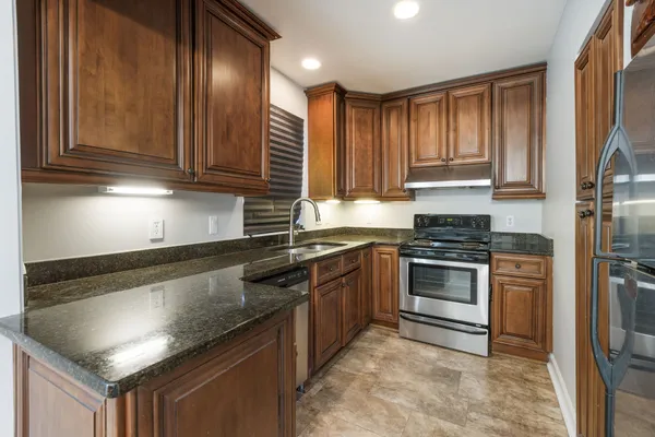 a kitchen with granite countertop stainless steel appliances a stove a sink and a refrigerator